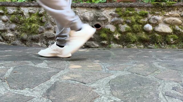 persona in abbigliamento casual che cammina su una pavimentazione in pietra vista livello del terreno