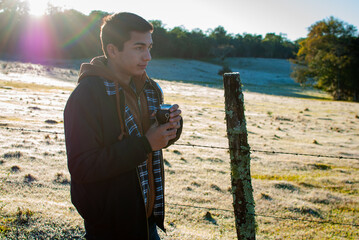 hombre joven en el campo con mate en la mano. mañana fría en el campo