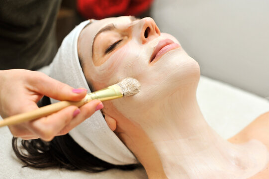 Woman relaxes as a beautician applies a fask mask during a beauty treatment