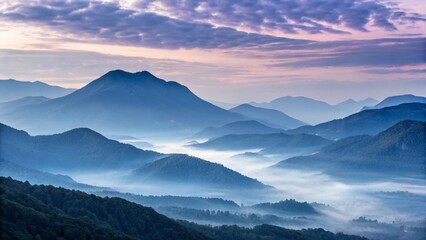 Obraz premium Blue fog blankets the mountain valleys under a cloudy sky