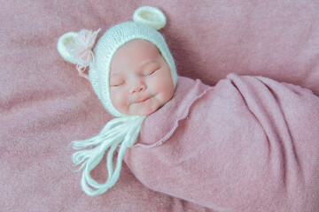 Newborn baby in white hat with bear ears sleeping sweetly