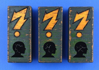Obraz premium Three wooden blocks, dark teal-green, display stylized lightning bolts and profiles of heads with electrical symbols