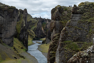 Fjaðrárgljúfur Canyon with a Winding River and Mossy Cliffs, Tourists Visible on the Rim, Capturing Iceland's Grand Scale