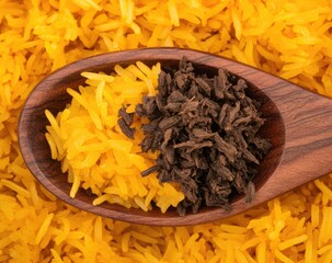 Wooden spoon holding yellow rice and dark spice