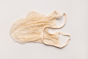 Eco-friendly string bag, shopping mesh bag of cotton threads on light gray background top view....