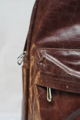 Close-up detail of a dark brown leather bag, highlighting its textured surface, front pocket, and...
