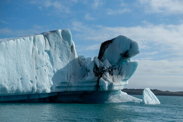Massive, sculpted iceberg with captivating blue and white tones floating in the deep blue waters of...