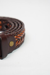 Close-up of a rustic two-tone braided leather belt in brown and tan, highlighting its intricate...