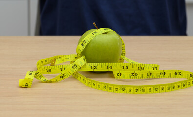 Diet weight loss concept, apple wrapped with measuring tape on table, count calories