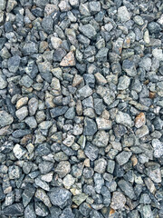Close-up view of various sizes of gravel stones, showcasing a mix of gray and earthy tones,...