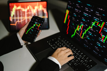 A trader analyzes real-time financial data on multiple devices, tracking stock charts, market trends, and investment strategies to manage risk, maximize profit, and grow a digital portfolio
