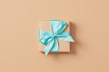 A gift wrapped in brown paper with a blue ribbon tied around it.