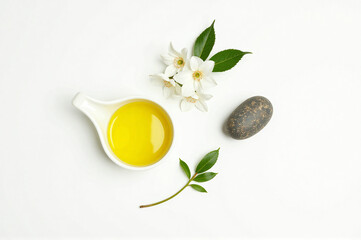 A white bowl of olive oil next to a small white flower.