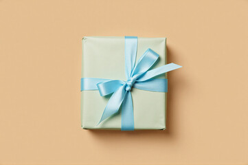 A gift wrapped in a light green paper with a blue ribbon tied around it.