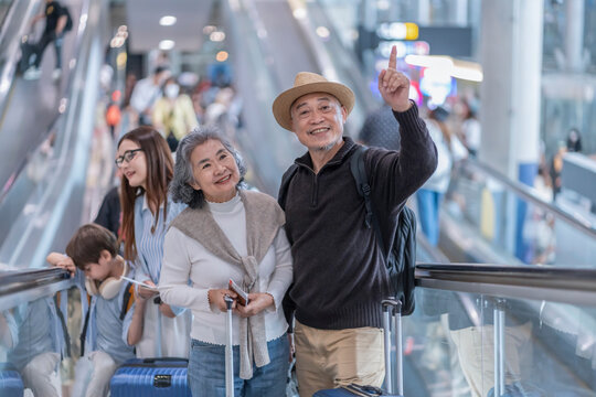 elegant asian senior couple on escalator together at the airport terminal,elderly passengers with modern lifestyle,going to journey on airlines travel for summer vacation trip