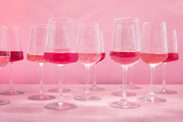 Rose wine tasting, a variety of hues and tints, side view on a pink background, many wineglasses, summer party
