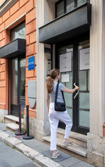 Woman Entering a Stylish Hotel Building During Daylight in a Vibrant City