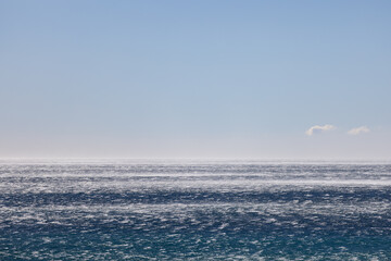 Extreme gale force wind gusts blowing across a dark blue ocean's surface creating sea spray and...