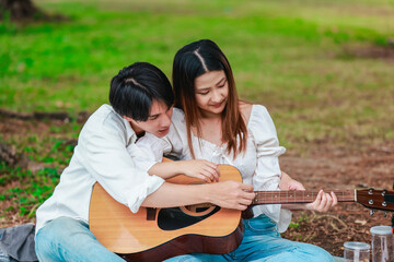 Asian Couple Playing Guitar Outdoors