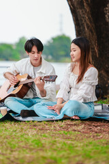 Asian Couple Playing Guitar Outdoors
