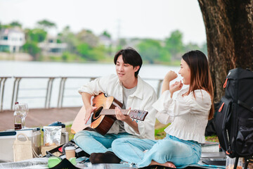 Asian Couple Playing Guitar Outdoors