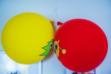 Close up view of red and yellow balloons with cartoon faces hanging on wall during birthday celebration. Sweden.