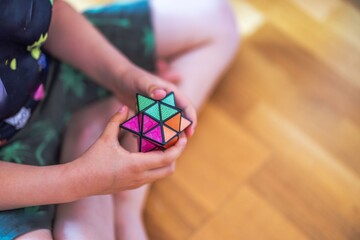 Child sitting on floor holding colorful star-shaped puzzle cube with both hands. Sweden.