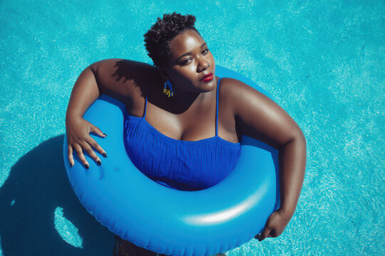 Playful summer portrait of plus-size woman with donut pool float