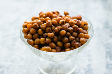 Delicious baked chickpeas in a transparent bowl on a light background. Healthy eating concept.
