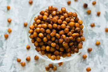 Delicious baked chickpeas in a transparent bowl on the table, on a light background with space for...