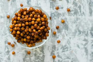 Delicious baked chickpeas in a transparent bowl on the table, on a light background with space for...