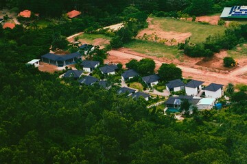 An aerial view showcases a cluster of modern homes nestled within the lush greenery surrounding...