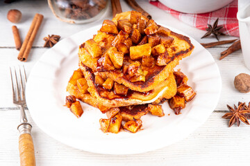 Sweet breakfast Apple Pie French Toast. Tasty delicious Stuffed French Toast with apple pie filling, cinnamon and ice cream scoop on top, with spices and fresh apples on table background