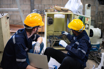 Blue collar workers at machine shop with welding robot arm.