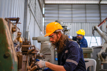 Blue collar workers at machine shop with welding robot arm.
