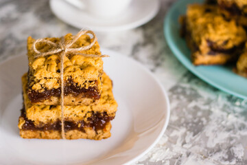 Delicious homemade pie with apple jam. Appetizing slices of grated pie with jam on a white plate on a light table