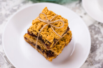 Delicious homemade pie with apple jam. Appetizing slices of grated pie with jam on a white plate on a light table