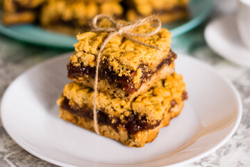 Delicious homemade pie with apple jam. Appetizing pieces of grated pie with jam on a white plate on a light table, many crispy pieces of pie on the background
