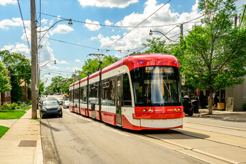 Public transit: Streetcar on a summer day in the Toronto Beaches neighbourhood white clouds blue...