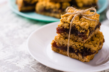 Delicious homemade pie with apple jam. Appetizing pieces of grated pie with jam on a white plate on a light table, many crispy pieces of pie on the background