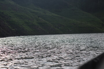 Waving surface of dark lake beside a mountain