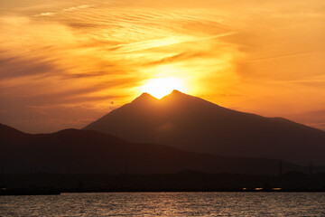 霞ヶ浦から望む夕暮れ時の筑波山と山頂に位置する太陽