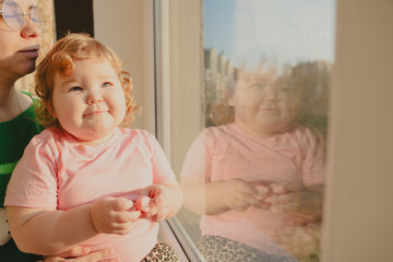 Child Enjoys a Moment by the Window With an Adult in Soft Evening Light
