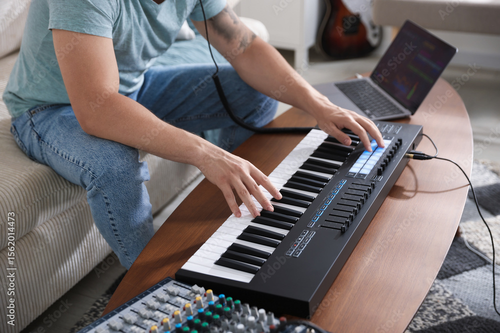 Poster man working with midi keyboard at table indoors, closeup
