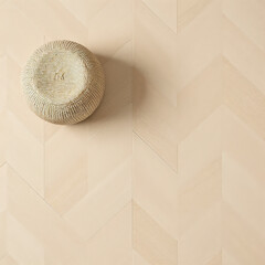 Light wood herringbone flooring with woven round stool for cozy natural interior
