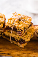 Delicious homemade pie with apple jam. Appetizing slices of grated pie with jam on a wooden board and coffee in a white cup on a light table.