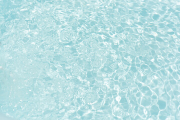 Blue water with ripples on the surface. Defocus blurred transparent blue colored clear calm water surface texture with splashes and bubbles. Water waves with shining pattern texture background.