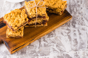 Delicious homemade pie with apple jam. Appetizing slices of grated pie with jam on a wooden board and coffee in a white cup on a light table.