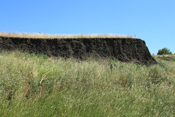 A grassy hill with a rock formation in the distance