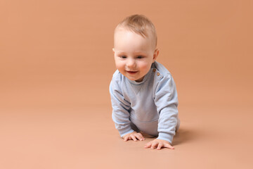 Cute little baby crawling on beige background, space for text
